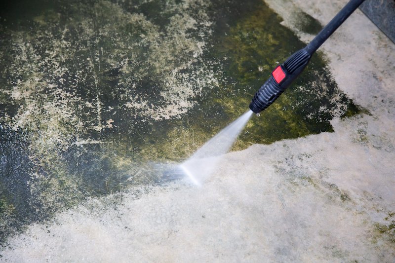 Power washing a concrete driveway clean